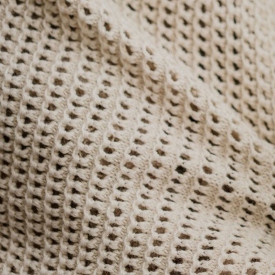 Tecido bege de malha com padrão de trama aberta e textura ondulada