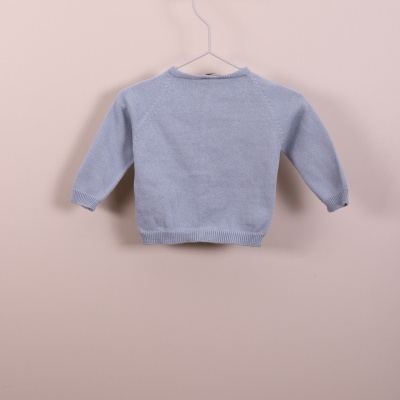 Camisola azul clara de malha para criança pendurada