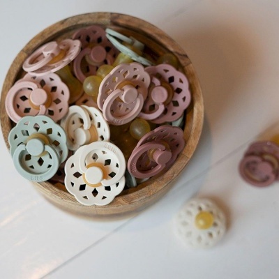 Biberões em silicone coloridos dentro de uma tigela de madeira