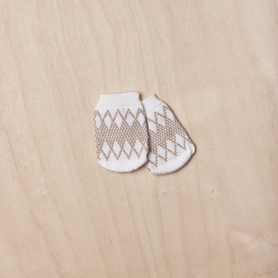 Meias para bebé brancas com padrão castanho sobre madeira clara