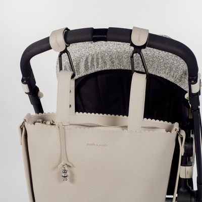 Mala bege de couro pendurada num carrinho de bebé preto com detalhes cinza