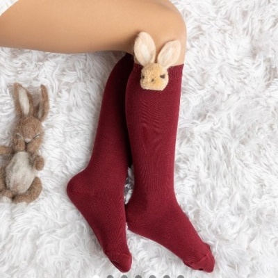 Meias longas vermelhas com detalhe de coelho bege e pelúcia de coelho ao lado