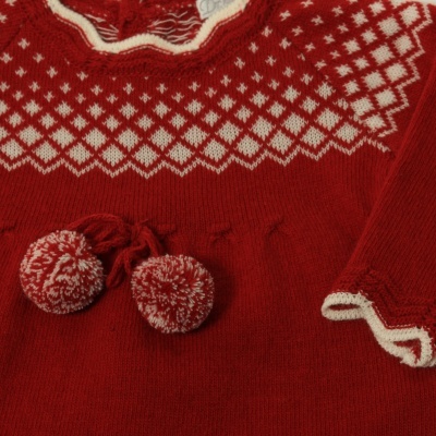 Roupa de criança vermelha com padrão branco e pompons