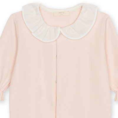 Macacão de bebé cor de rosa claro com gola branca franzida.