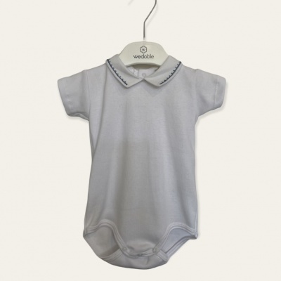 Body branco para bebé com gola azul escuro pendurado num cabide branco.