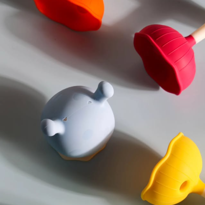 Objetos de silicone coloridos com texturas variadas sobre fundo cinza ondulado