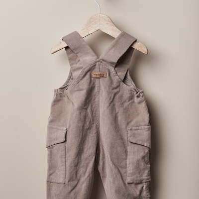 Jardineiras infantis castanhas em tecido de veludo cotelê penduradas em cabide de madeira