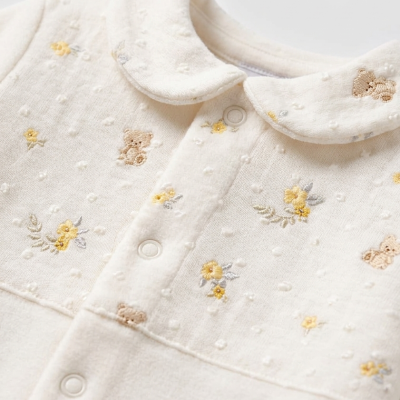 Babygrow creme com bordados de flores e ursos e gola peter pan.
