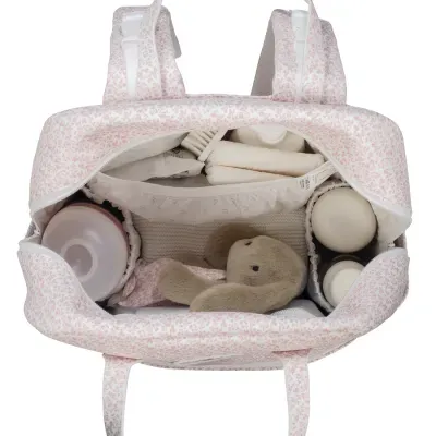 Mala de bebé rosa clara com padrão floral e interior organizado com biberões, fraldas e brinquedo de peluche.