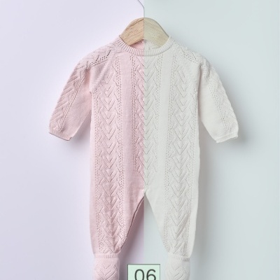 Macacão de bebé metade rosa claro metade creme em cabide de madeira com fundo dividido