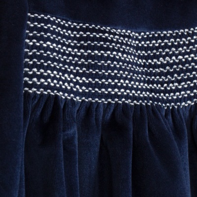 Vestido azul escuro de veludo com gola branca e detalhes acolchoados em branco e azul.