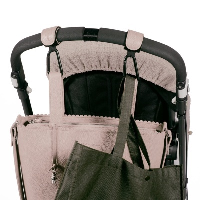 Carrinho de bebé com saco rosa claro e saco tecido cinza pendurados na alça