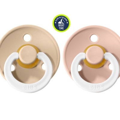 Duas chupetas redondas bege e rosa com argolas brancas e selo NIGHT TIME acima