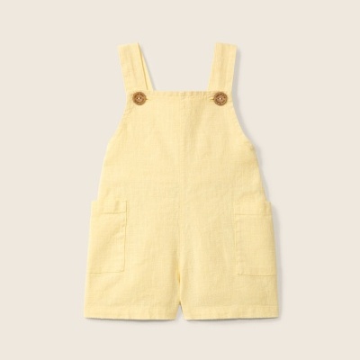 Macacão curto amarelo claro para criança em linho com botões de madeira.