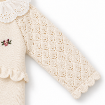 Manga de camisola creme com padrão losangos e bordado de flores.
