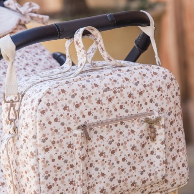 Mala floral bege e castanha pendurada num carrinho de bebé