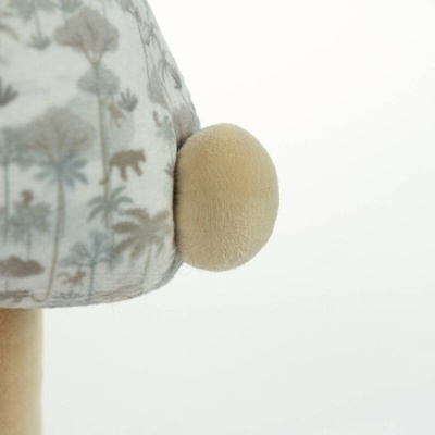 Detalhe lateral de peluche com padrão de animais e árvores e pompom bege