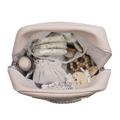 Bolsa bege aberta com fraldas, brinquedo de pelúcia, escova, saco de tecido e anel de madeira visíveis no interior