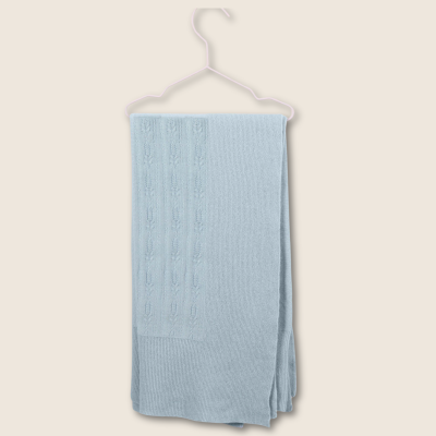 Lençol de malha azul claro com padrão trançado pendurado num cabide rosa