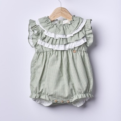 Macacão de bebé verde e branco com folhos pendurado em cabide de madeira