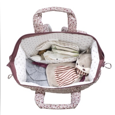 Mala rosa floral aberta com boneca de peluche, lenços e escova dentro