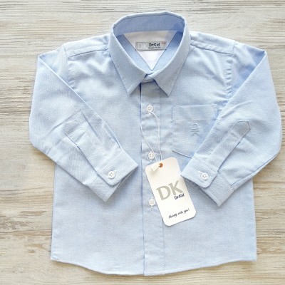 Camisa azul clara de criança com bolso e etiqueta DK sobre madeira clara