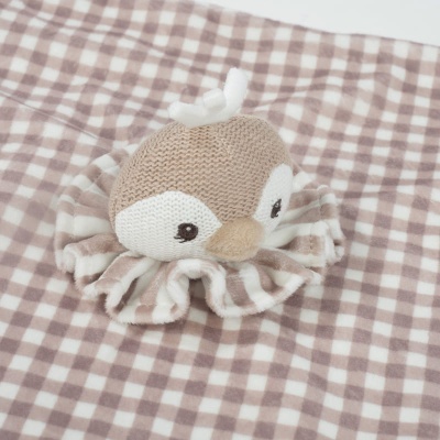 Brinquedo de peluche polvo sobre tecido xadrez castanho claro e branco