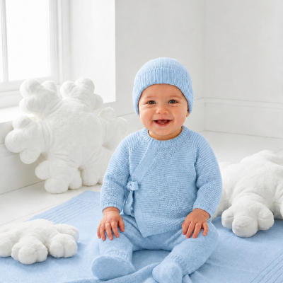 Bebé com roupa de malha azul claro sentado em tapete azul e almofadas em forma de flocos de neve