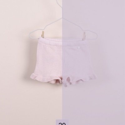 Shorts brancos de criança pendurados num cabide metálico