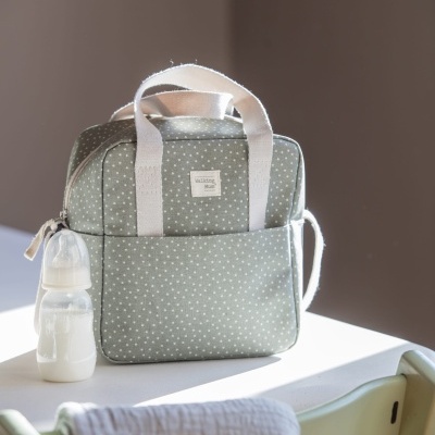 Mala térmica cinza com pontos brancos, mamadeira e tecido sobre cadeira e mesa