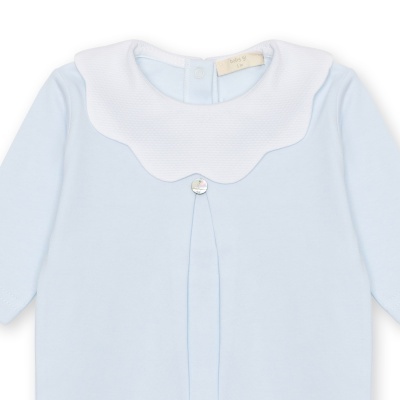 Pijama de bebé azul claro com gola branca ondulada e botão prateado.