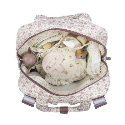 Mochila para bebé bege com padrão floral castanho e objetos de bebé no interior