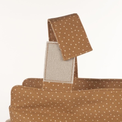 Detalhe de tecido castanho com pontos brancos e fecho de contacto branco