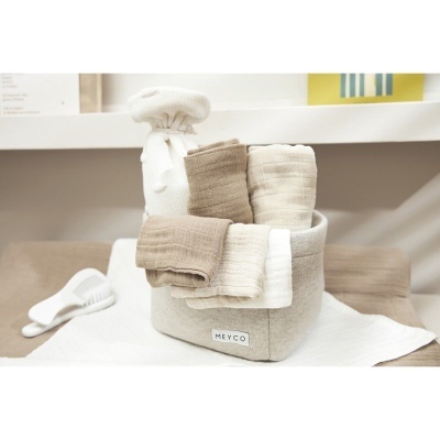 Cesto de tecido com toalhas creme e bege, roupa branca com pompons e pente branco