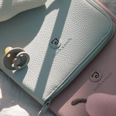 Bolsa azul clara e rosa em pele texturada com chupeta e bonecos de tecido em fundo claro