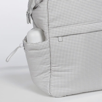 Mochila cinza e branca com padrão xadrez e bolso lateral acolchoado com garrafa branca