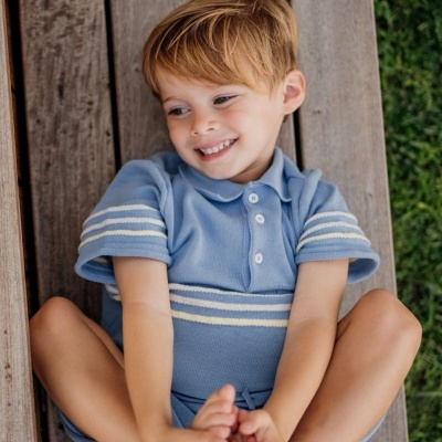 Camisola de malha azul clara com riscas brancas vestida por criança num banco de madeira.