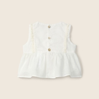 Blusa branca para criança com botões na parte de trás e folhos laterais