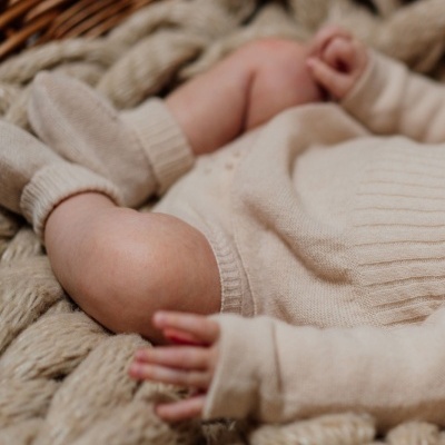 Roupa de bebê bege em malha sobre manta tricotada