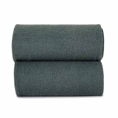 Manta verde escuro tricotada dobrada sobre fundo branco