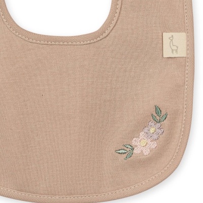 Babete de tecido bege com bordado de flores e etiqueta com desenho