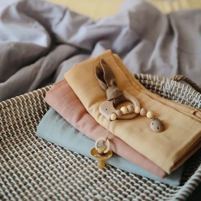 Três panos de tecido coloridos numa cesta com brinquedo de madeira