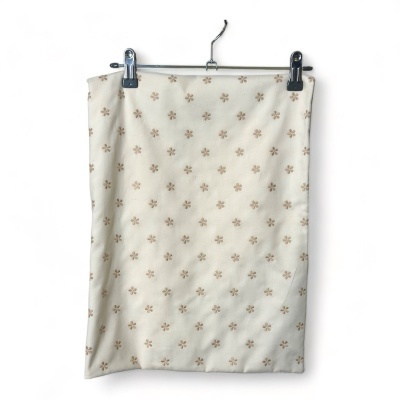 Saia branca com flores castanhas pendurada num cabide branco.