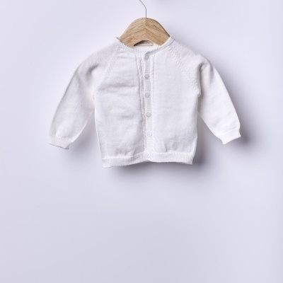 Casaco de malha branco para bebé pendurado num cabide de madeira