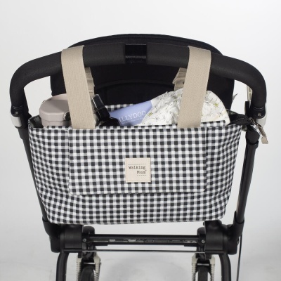 Bolsa organizadora preta e branca com padrão xadrez presa a carrinho de bebé
