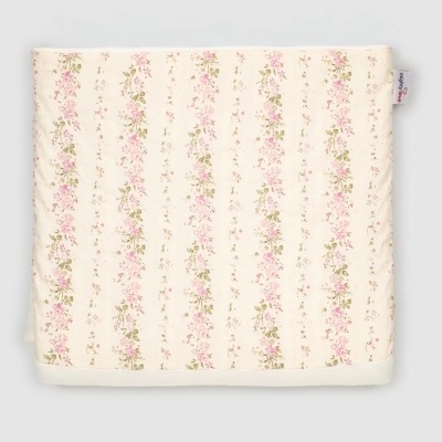Manta com padrão floral rosa e verde sobre fundo creme