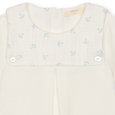 Babygrow branco com babete com padrão de âncoras azuis e botões brancos.