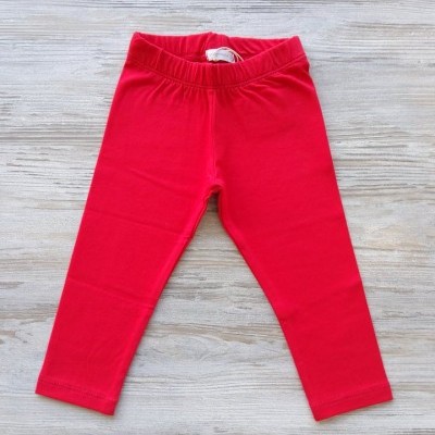 Leggings vermelhas para criança sobre fundo de madeira clara