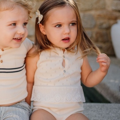 Crianças em roupa de bebé creme com fundo de parede de pedra