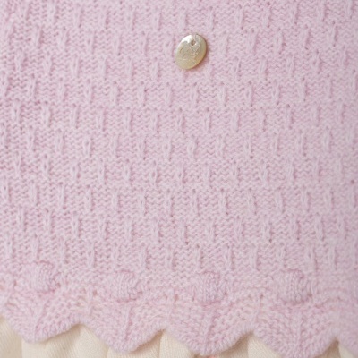 Detalhe de peça de roupa rosa clara com gola creme e saia com flores rosa
